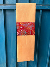 Load image into Gallery viewer, A yellow tea towel made from European linen and featuring the art work Flowers in the desert by Australian Indigenous artist Lauren Doolan. The tea towel is hanging on a deep blue coloured wall.