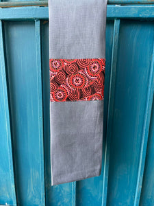 A blue tea towel made from European linen and featuring the art work Salt Lake by Australian Indigenous artist Heather Kennedy. The tea towel is hanging on a deep blue coloured wall.
