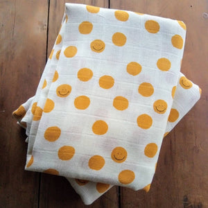 double muslin baby wrap featuring smiley faces in yellow. Decorate your nursery and nest for baby. Gifts.