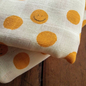 double muslin baby wrap featuring smiley faces in yellow. Decorate your nursery and nest for baby. Gifts.