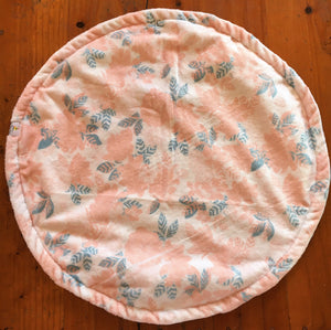 a round cat mat made with 3 layers of minky. Featuring a floral design in a pale pink with blue, grey leaves on a pale cream background